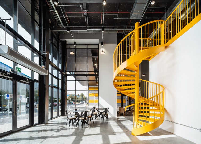 Cafe space with large windows and yellow spiral staircase