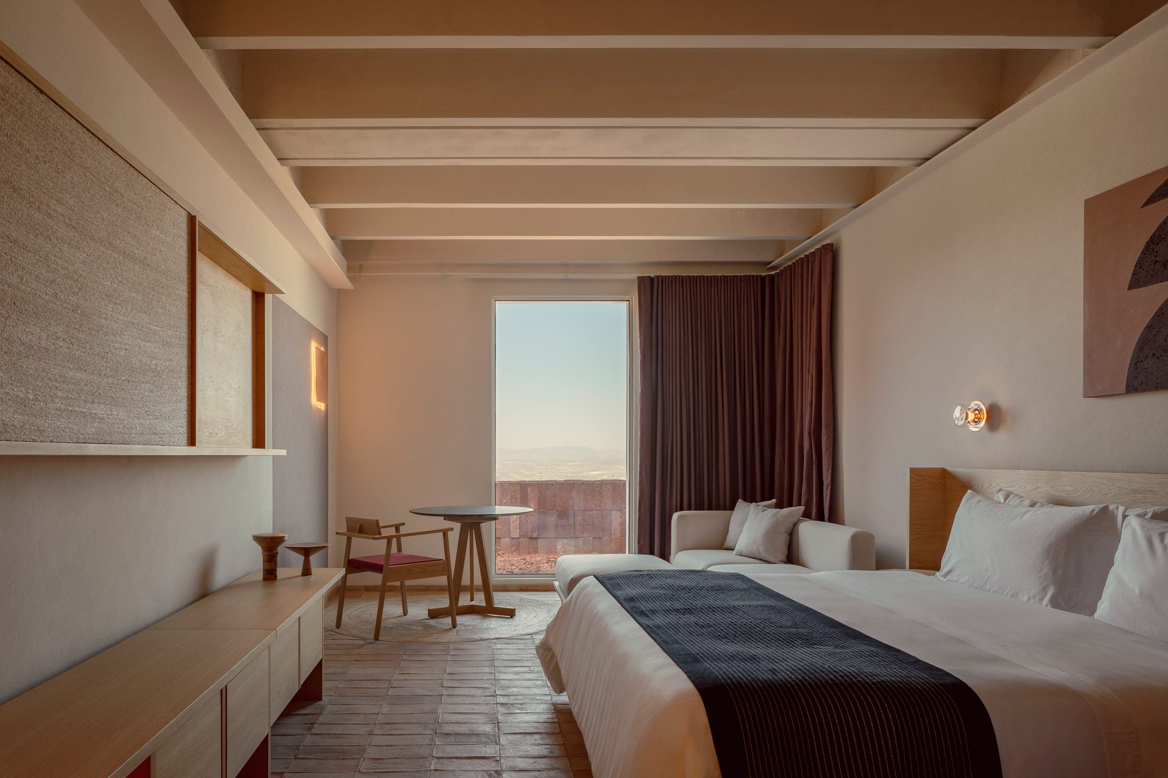 A bedroom outfitted with beige textiles and walls with accents of earthen tones