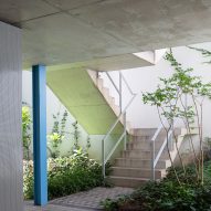 Concrete staircase in a courtyard supported by blue columns