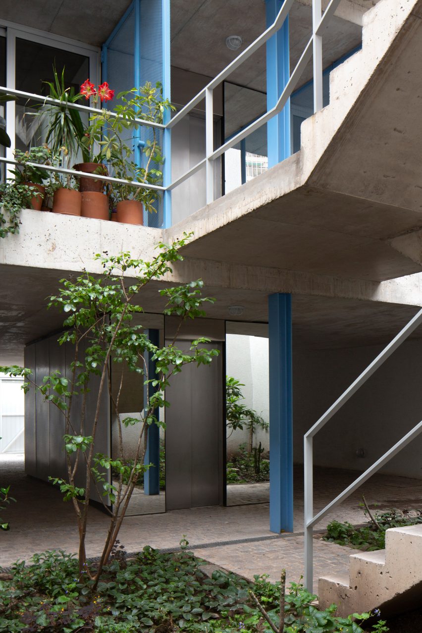Courtyard surrounded by concrete staircases supported by blue steel columns