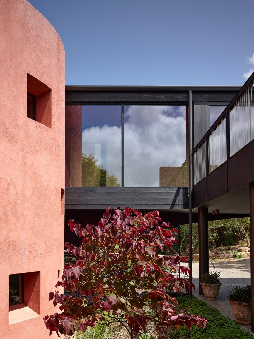 Двор в окружении черного бревенчатого дома в розовых тонах
