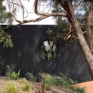 Charred timber exterior of Somers House with a circle window