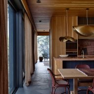 Timber-clad kitchen with wooden table and gold pendant lights