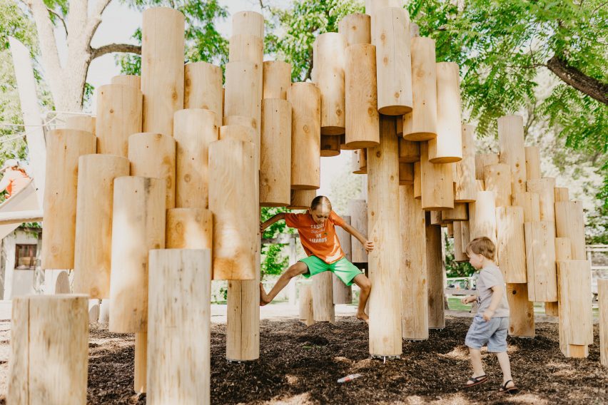 A child navigates a structure made of logs in a playground
