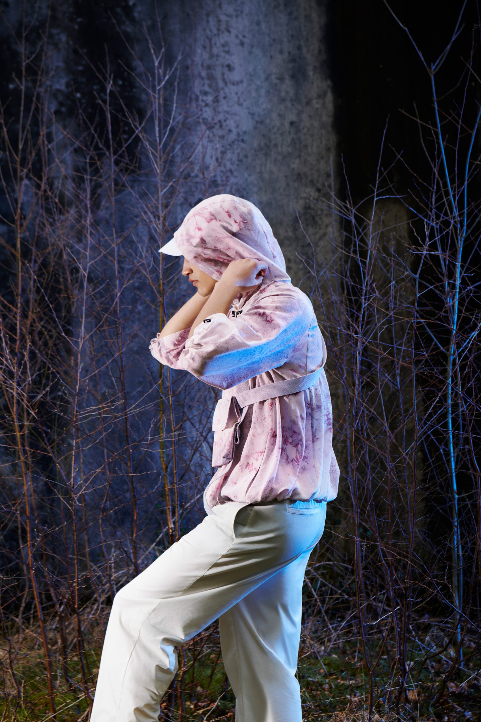 Campaign photo of a person wearing the bacteria-dyed NPOL Exploring jacket lit up while walking through a forest at night