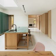 Kitchen with white walls and floors, green wall panels and a wood island