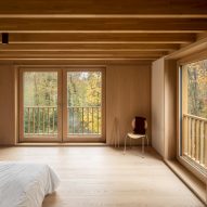 Timber-clad bedroom with windows overlooking a wooded area