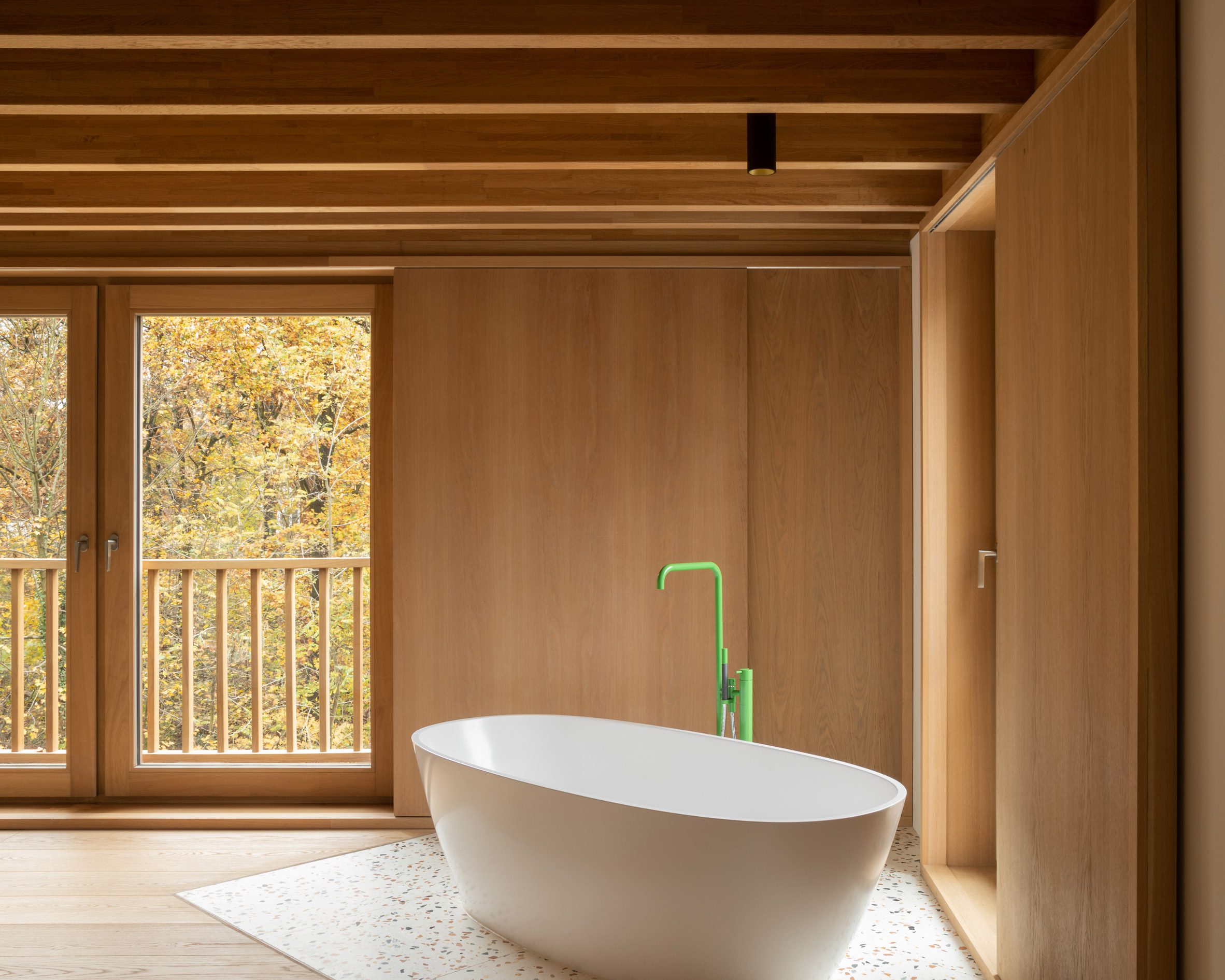 Interior de la habitación de madera con bañera independiente blanca y grifo verde