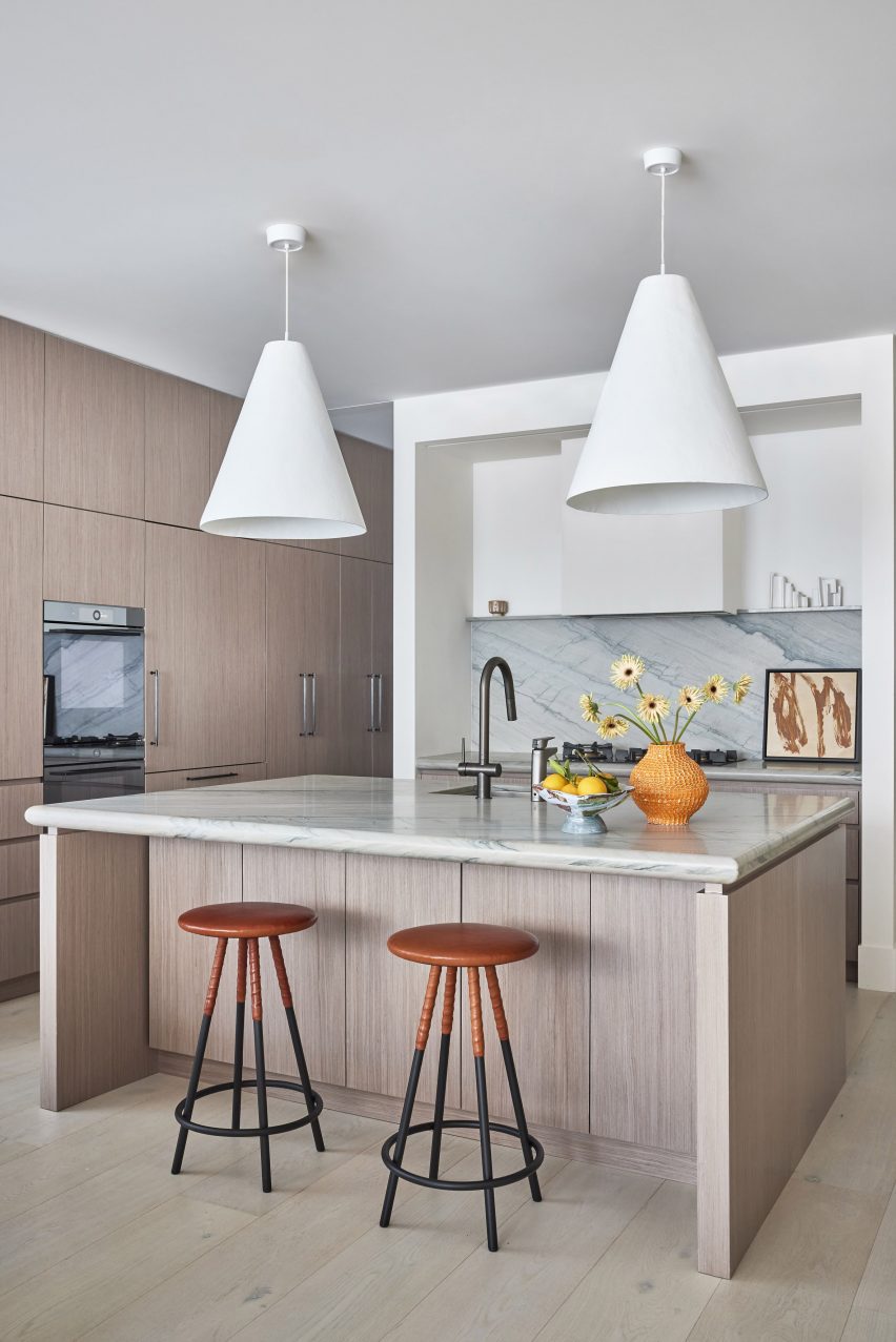 A kitchen with light wood cabintry, triangular lights, and a large island