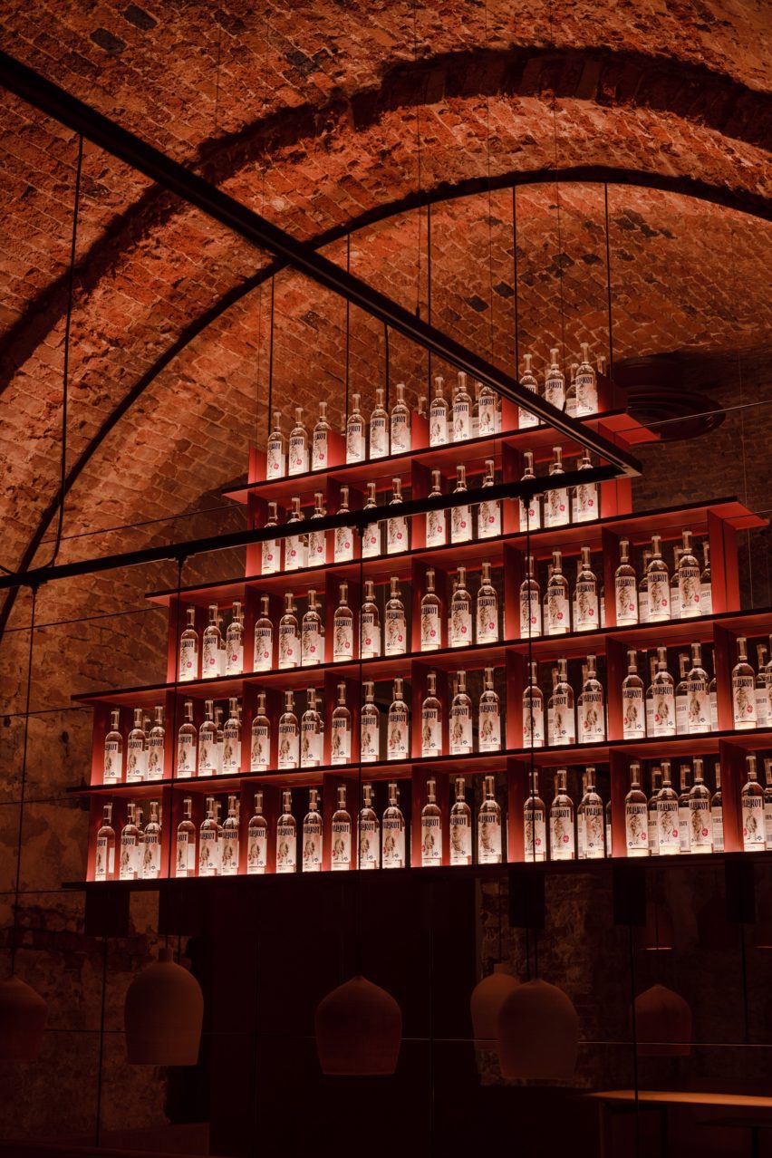 Red bottle display shelving inside a vaulted brick space