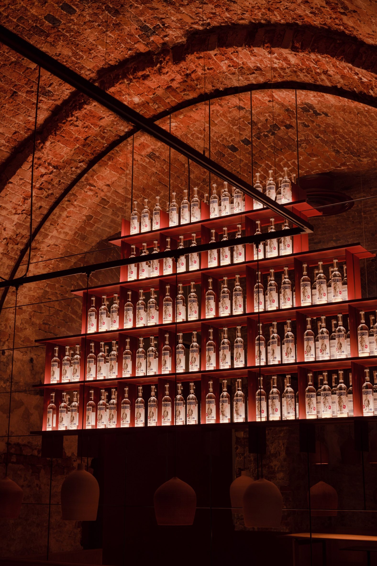 Red bottle display shelving inside a vaulted brick space