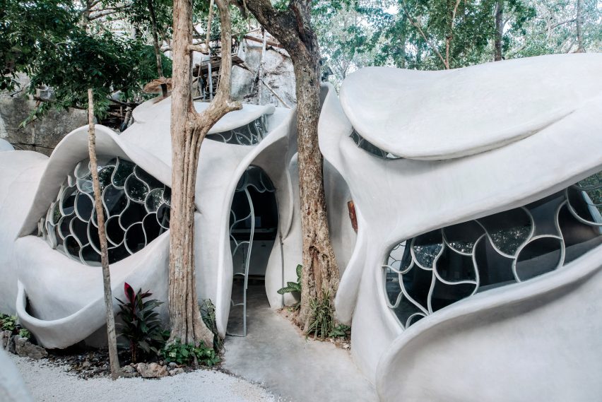 A curving building made of concrete that wraps around trees