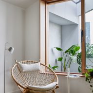 Lounge chair next to a wood-framed window overlooking a balcony