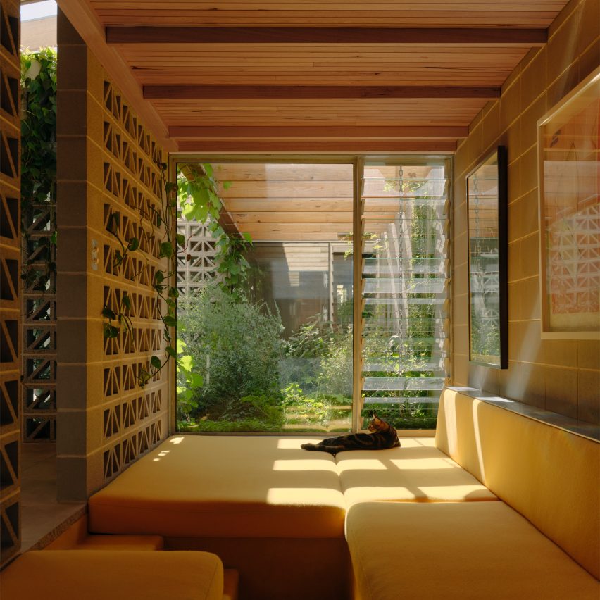 Yellow cushioned window seating nook with perforated breeze block walls by Architecture Architecture