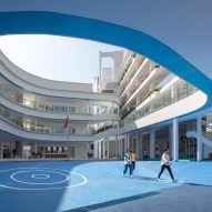 Curving classrooms surrounding a blue playground at Kindergarten of Museum Forest by Atelier Apeiron
