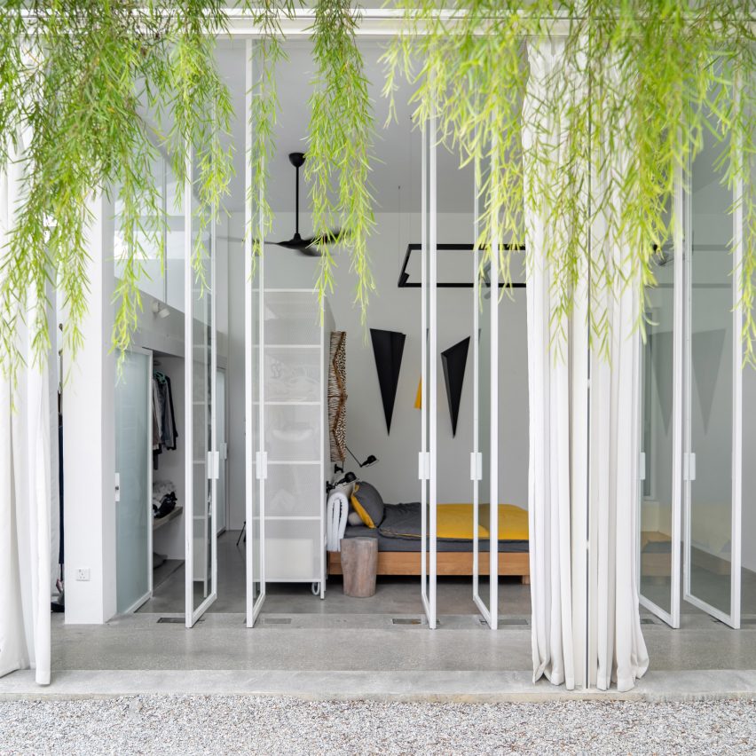 Courtyard with white-framed glass doors opening into a bedroom with hanging plants