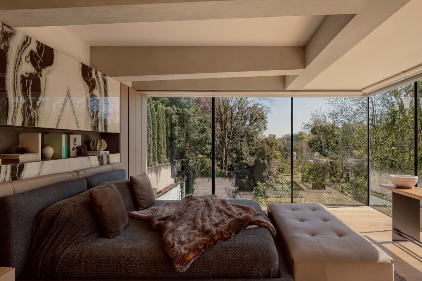 A bedroom with dark furnishings and floor-to-ceiling windows offering garden views