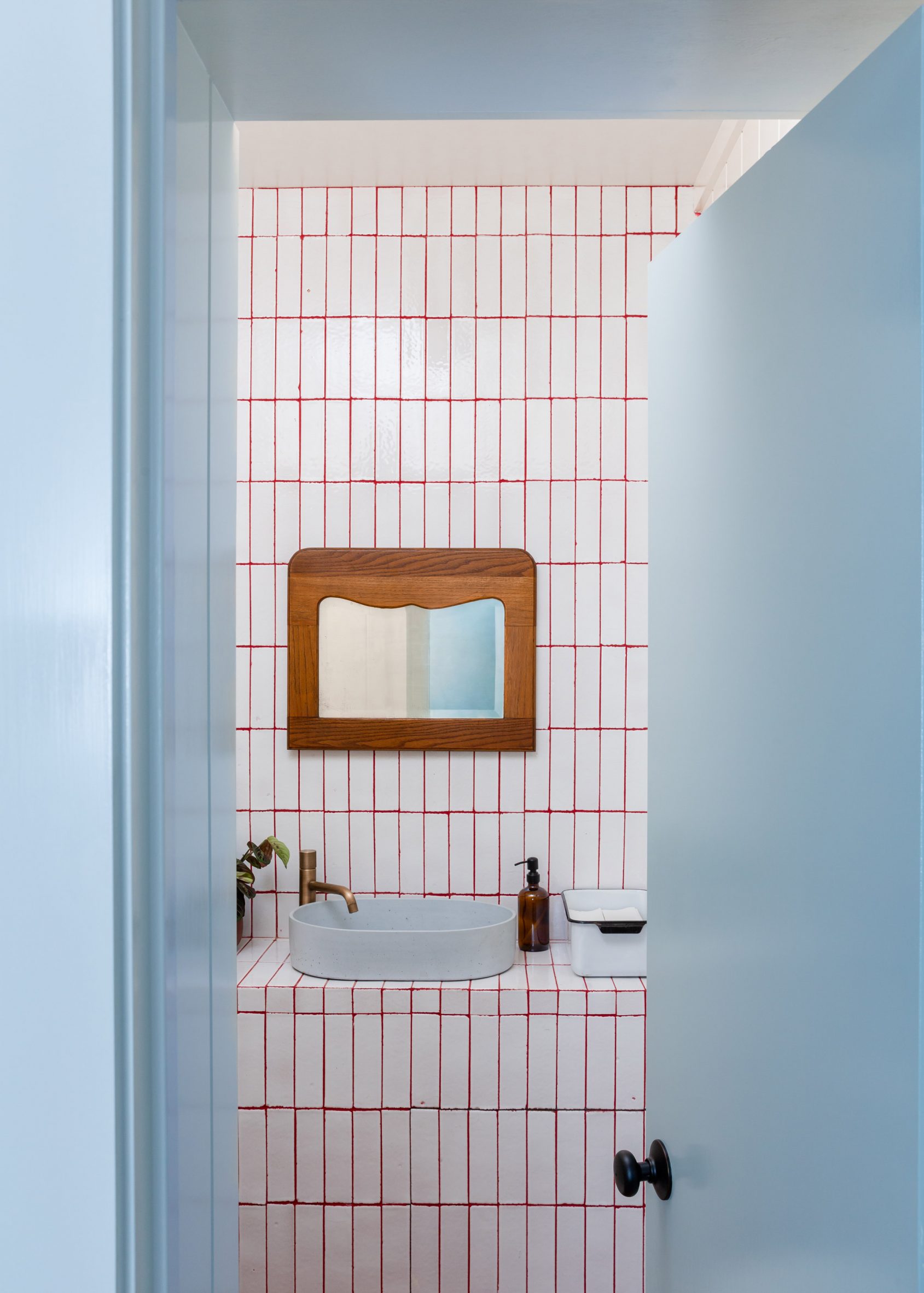 White-tiled bathroom viewed through powder-blue door frame