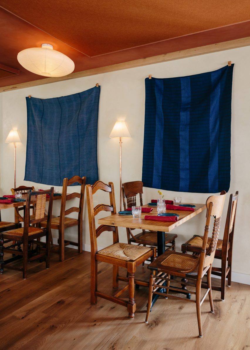 Blue tapestries hang above wooden tables and chairs