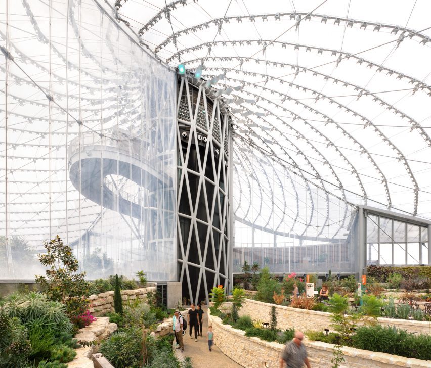 A public greenhouse with tiered planting beds and a soaring rood