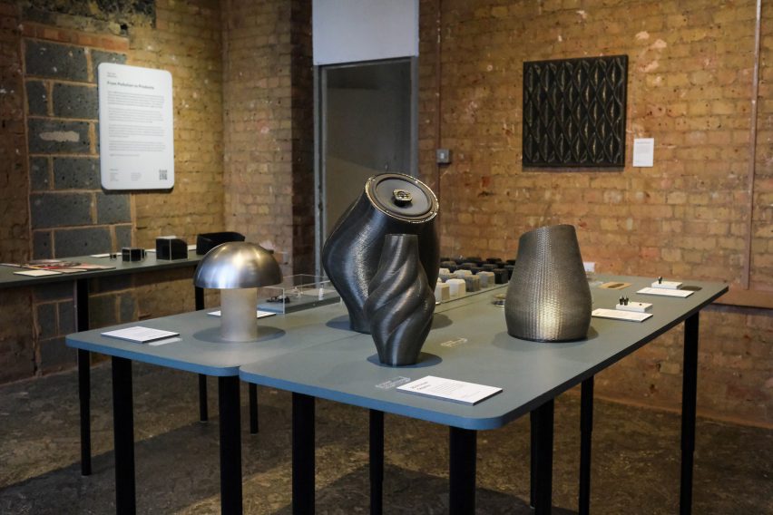 Photo of the Tyre Collective exhibit at Material Matters in London 2023, showing a seried of large, 3D-printed dark grey forms sitting on a table