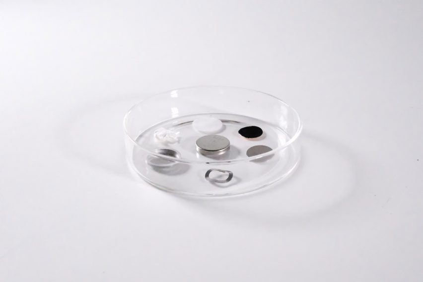 Photo of a single-cell coin battery and battery components in a circular clear dish