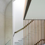Frosted glass staircase in a concrete room with brass banister