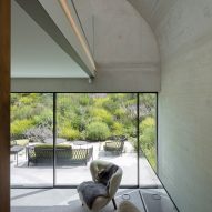 Concrete living space with lounge chairs and large glass doors leading to an outdoor terrace