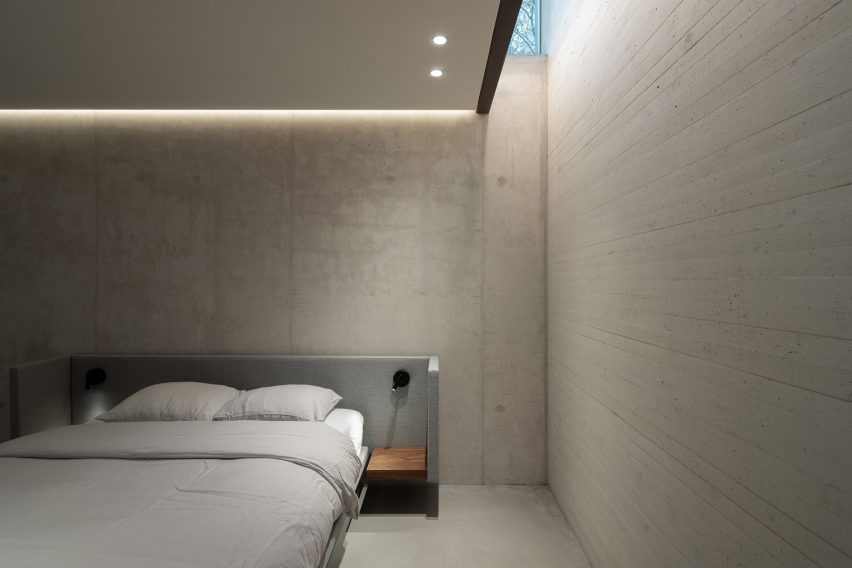 Bedroom with concrete walls and a narrow skylight