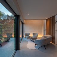 Concrete living room with lounge chairs and floor-to-ceiling glass doors leading to a patio