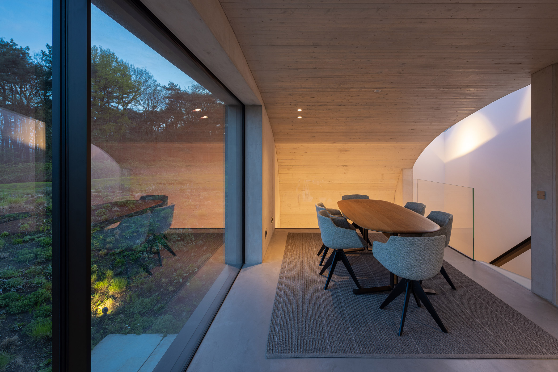 Concrete dining area with floor-to-ceiling glass doors leading to a patio