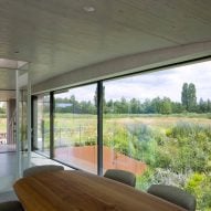 Concrete dining room with large windows overlooking a grassy landscape