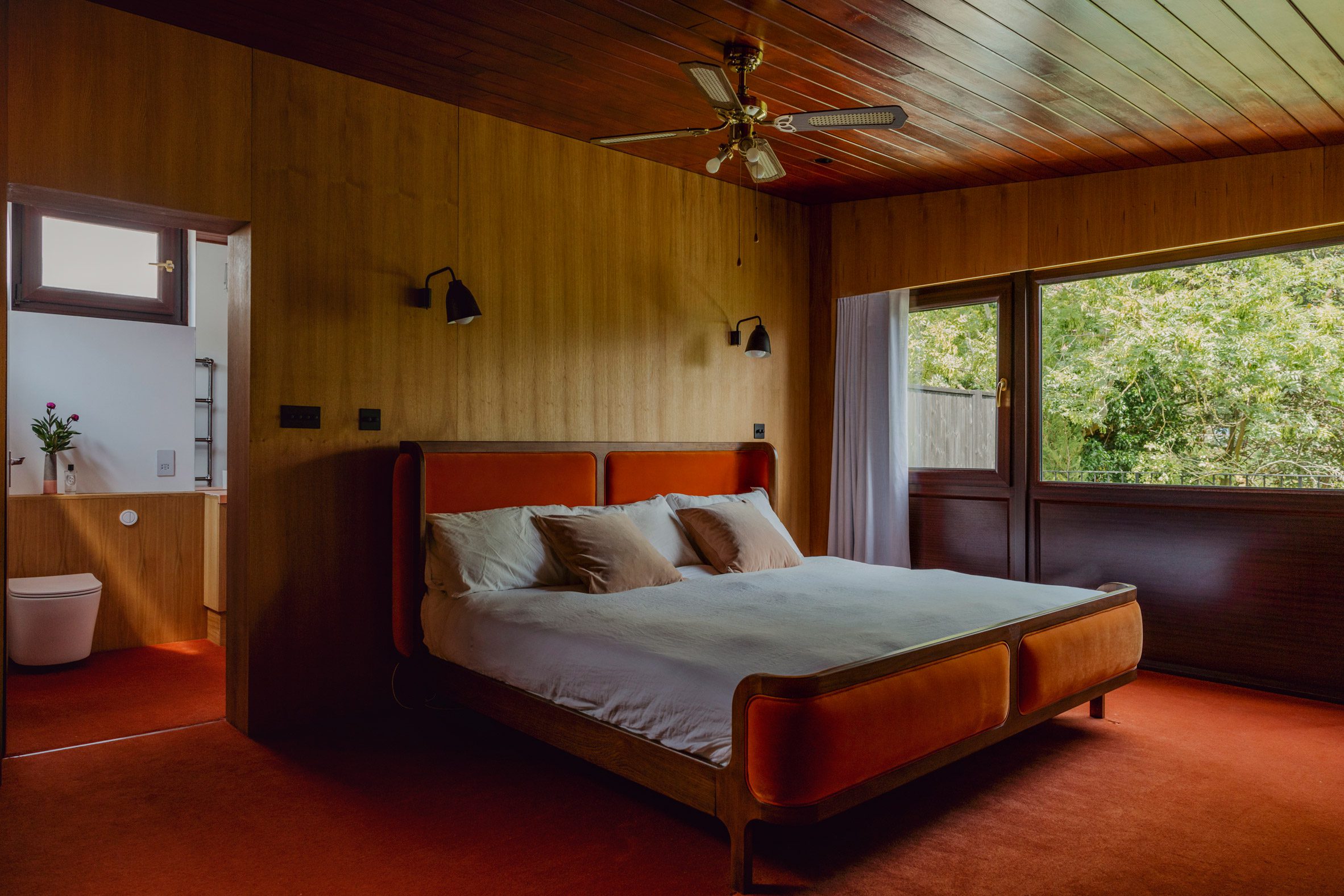 Bedroom in Zero House with wood-panelled walls and an orange carpet