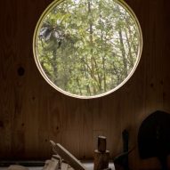 Circular window in a timber wall overlooking a forest