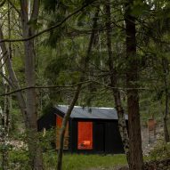 Black timber cabin in a forest by BABELStudio