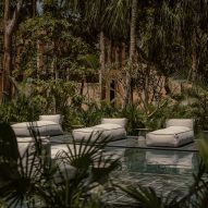 A pool in a jungle with cushion lounge chairs