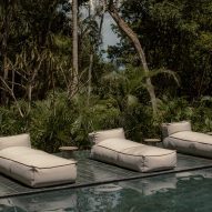 A pool in a jungle with cushion lounge chairs