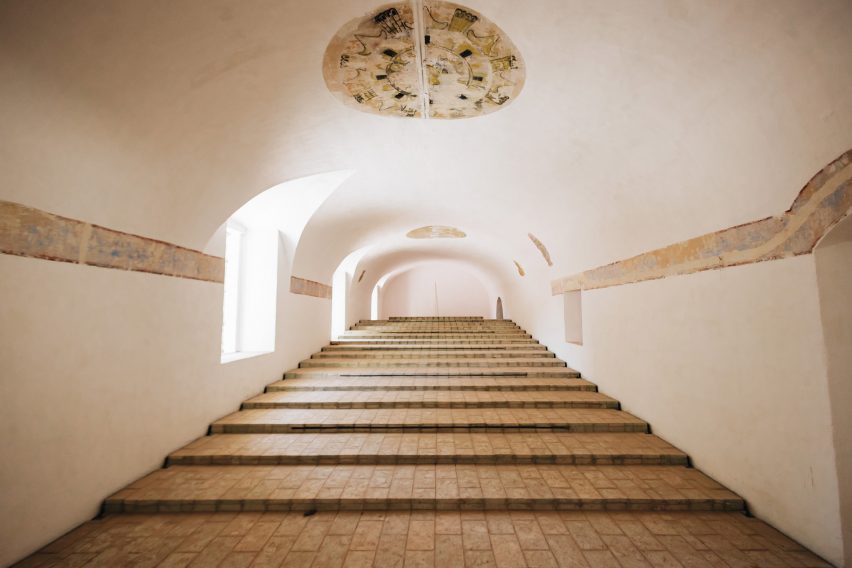 Deep steps ascending through a long vaulted plaster room