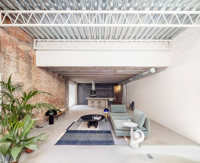 Open-plan living room with a brick wall and ceiling with exposed metal structure
