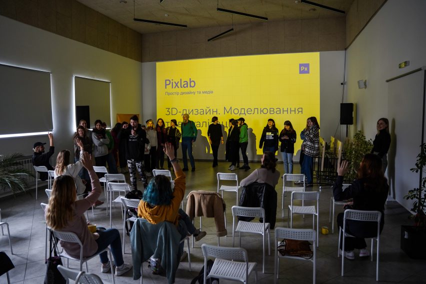 Photo of a gathering taking place in an event space at Pixlab in Lviv, with participants sitting in chairs raising their hands to ask questions
