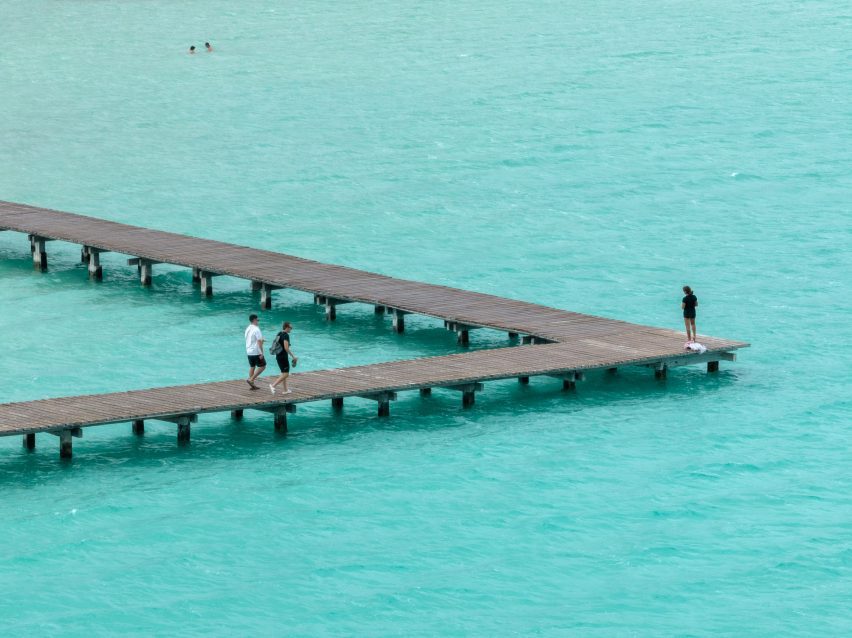 Boardwalk with people walking over light blue water