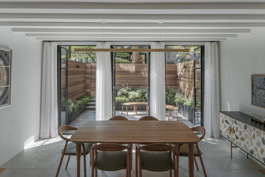 Dining area open to a bluestone patio enclosed with cedar panels