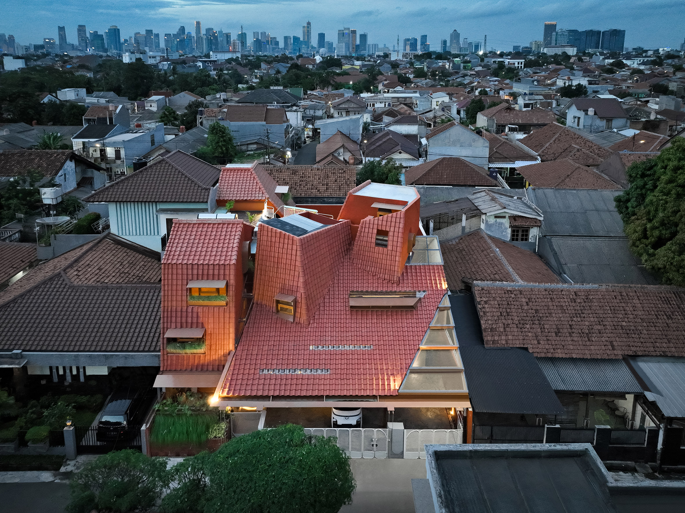 Distracted House with an angular red-tiled roof by Ismail Solehudin Architecture