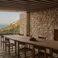 Wood dining table in a stone room with a terrace overlooking the sea