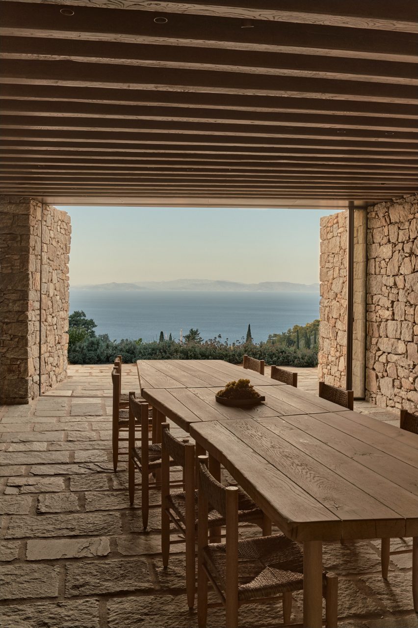 Wood dining table in a stone building with a terrace overlooking the sea