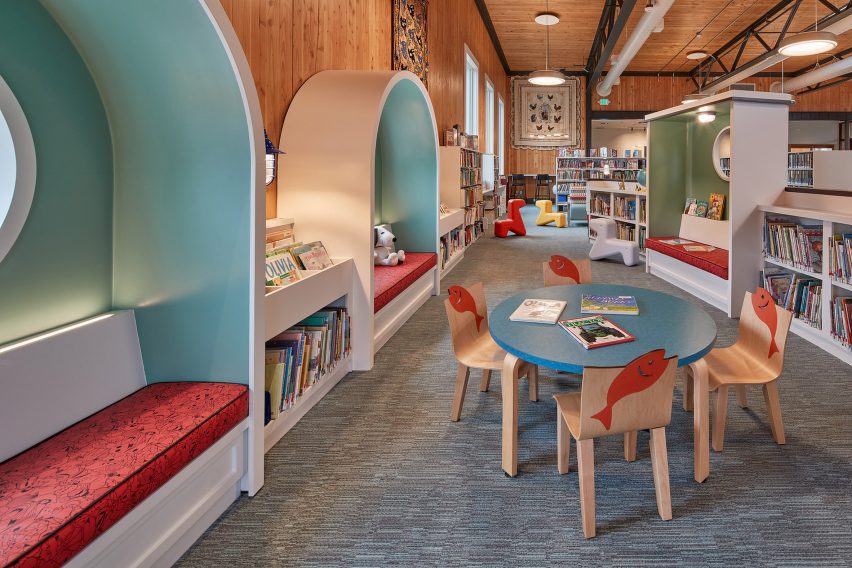 A childrens corner of a library with light blue shelving and little chairs