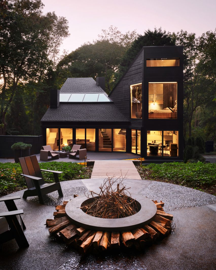 Exterior view of black modernist home with a firepit in the foreground