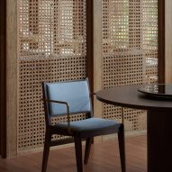 Upholstered wooden chair in front of a rattan screen