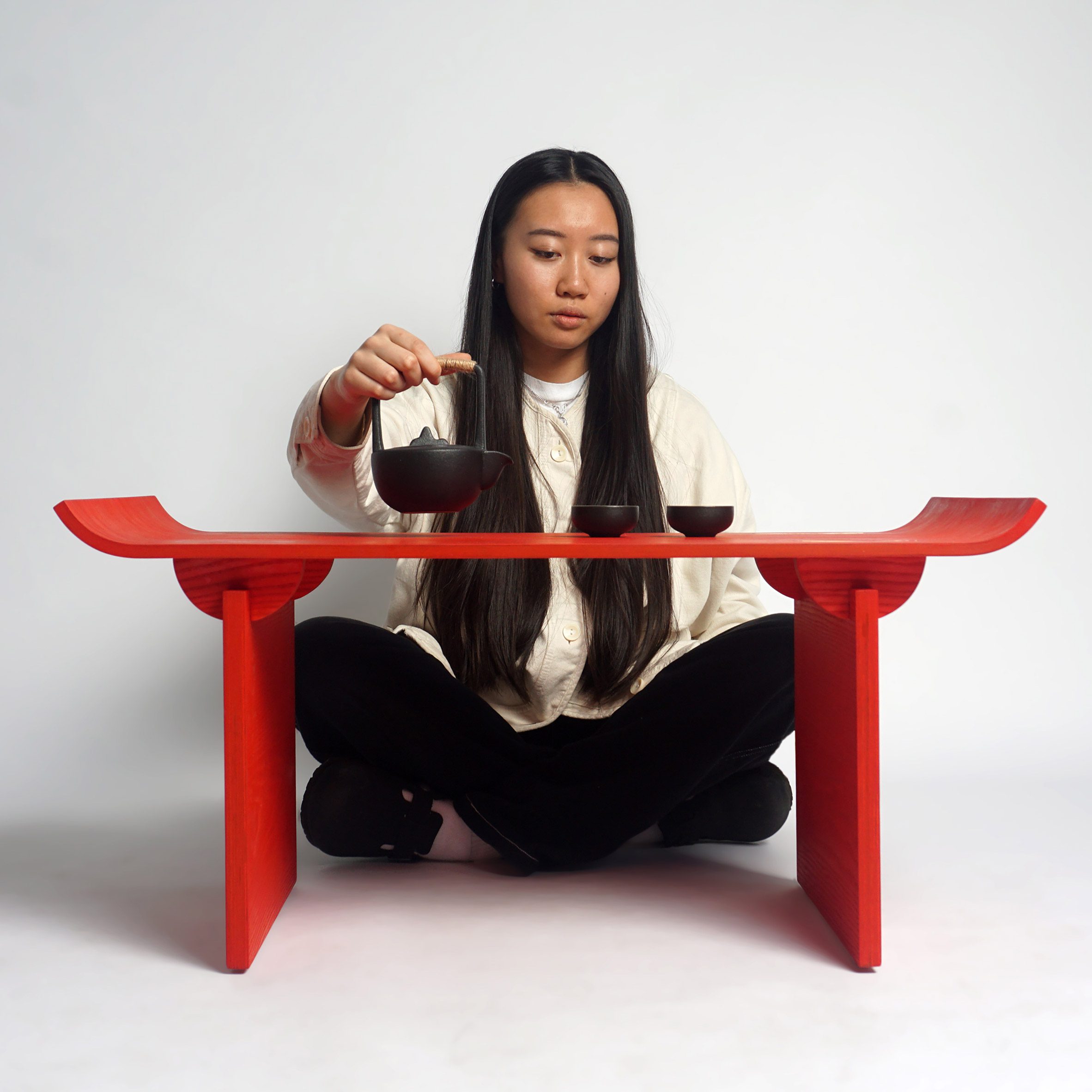 Person sitting at red table pouring tea