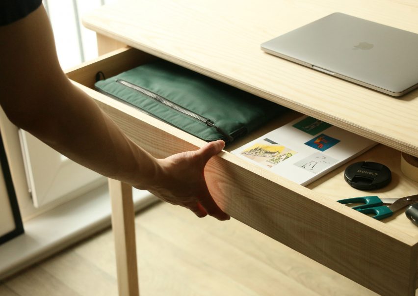 Photograph showing hand opening drawer in desk